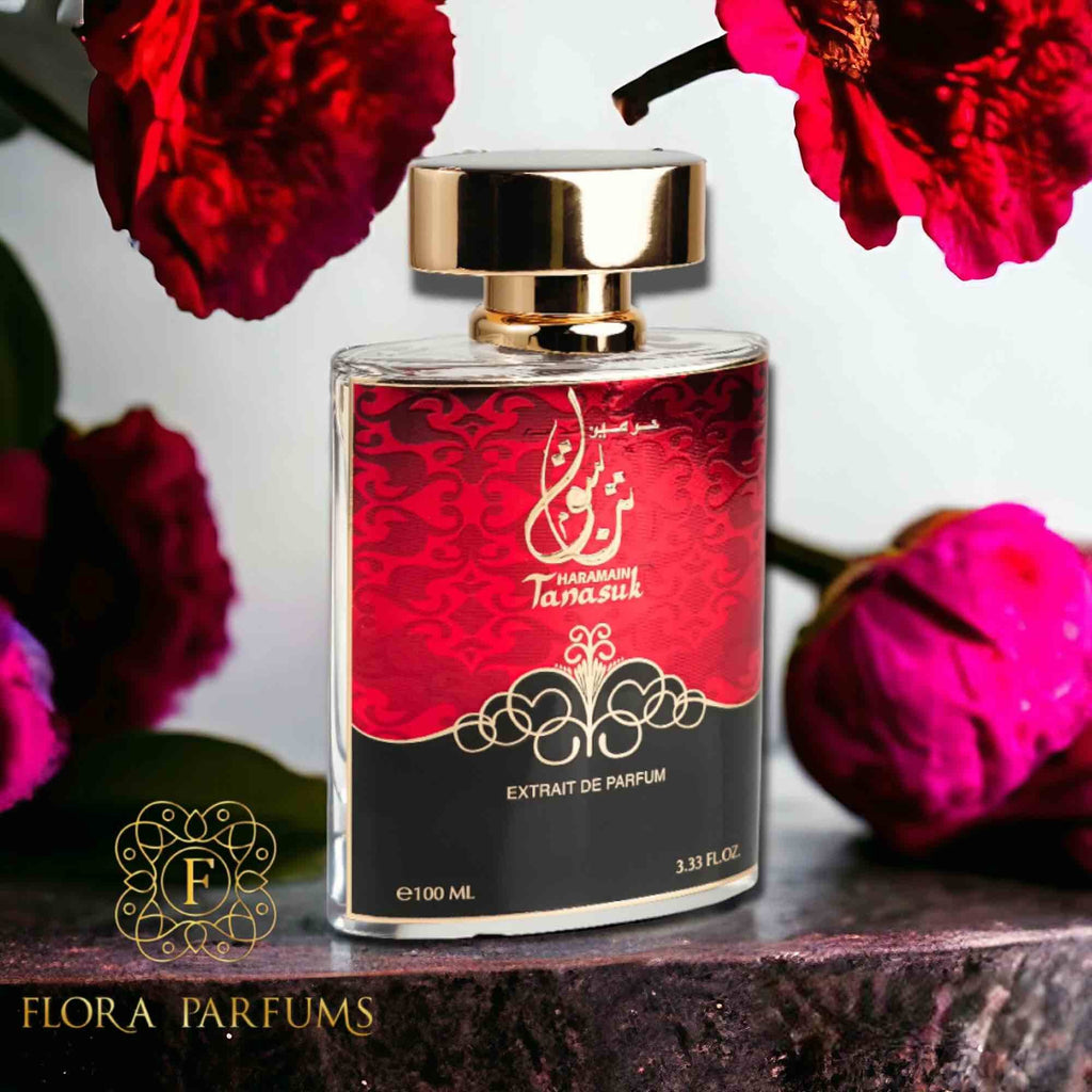Perfume bottle with red label and gold cap on a dark surface with red flowers in the background