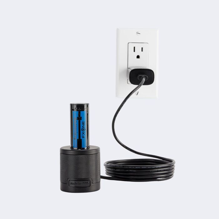Black cylindrical device with blue label plugged into a wall outlet on a white background