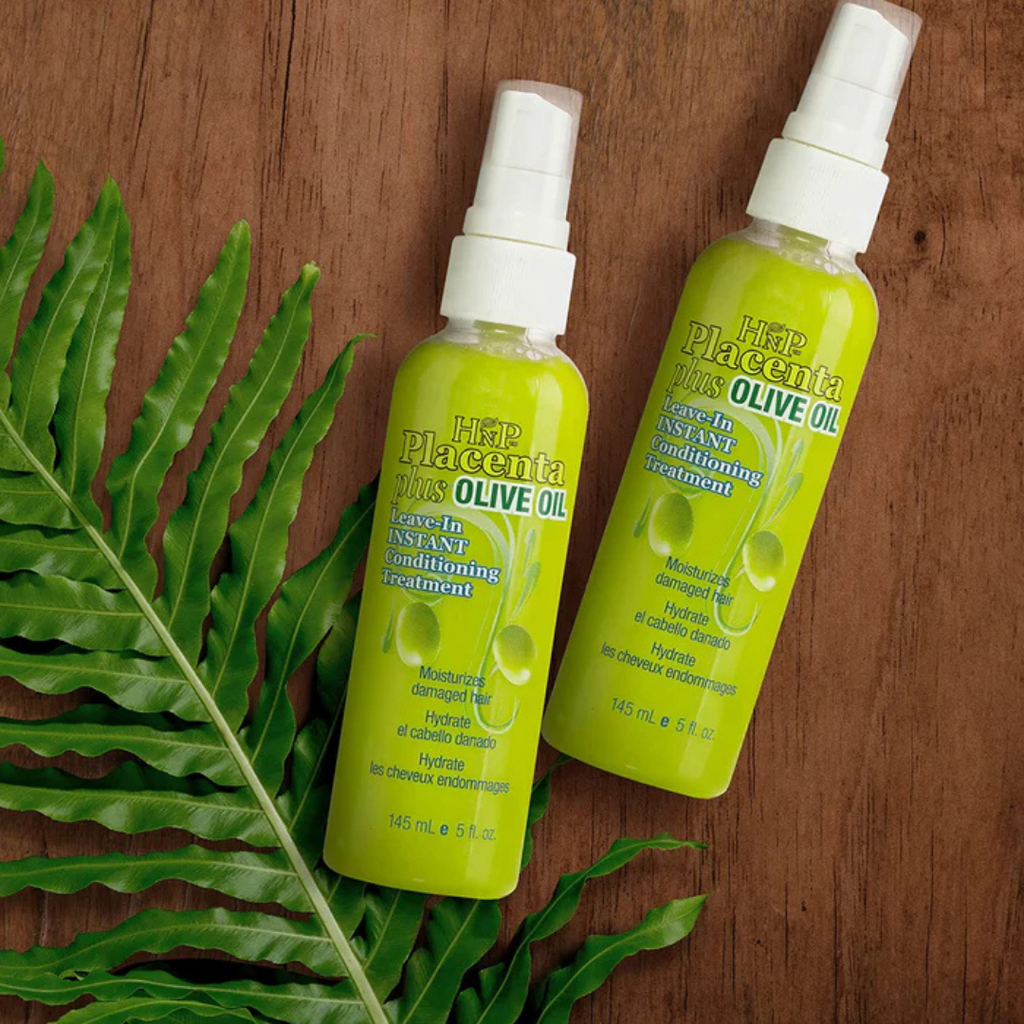 Two bottles of Hair Placenta Olive Oil product on a wooden surface with green leaves.